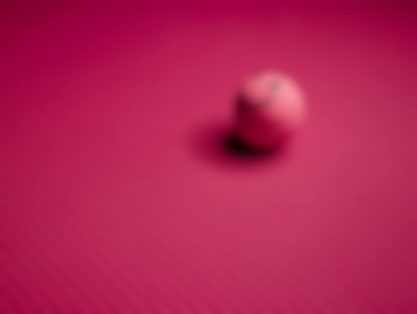 A pink bouncy ball with a smile sitting on a pink background