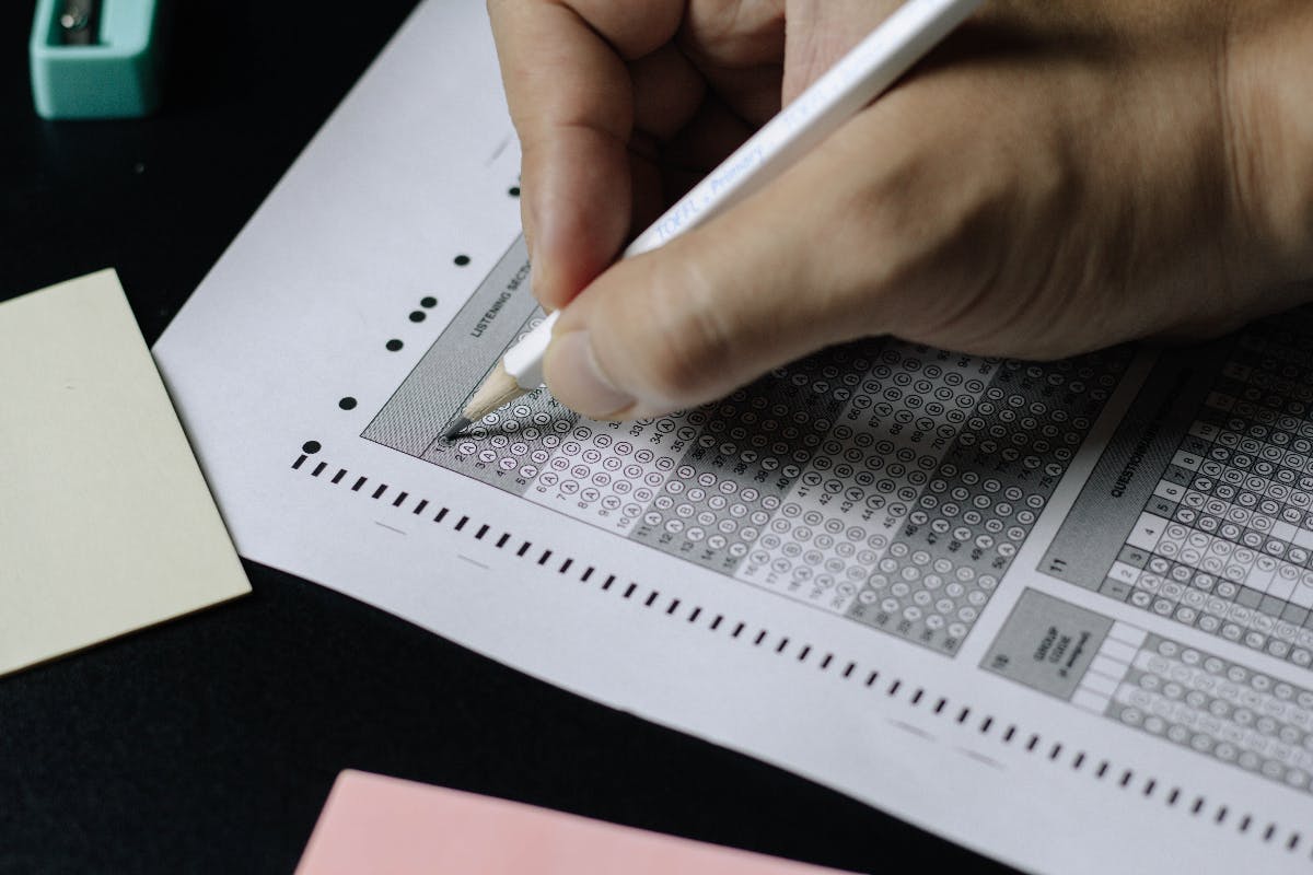 a hand with a number 2 pencil taking a standardized test.