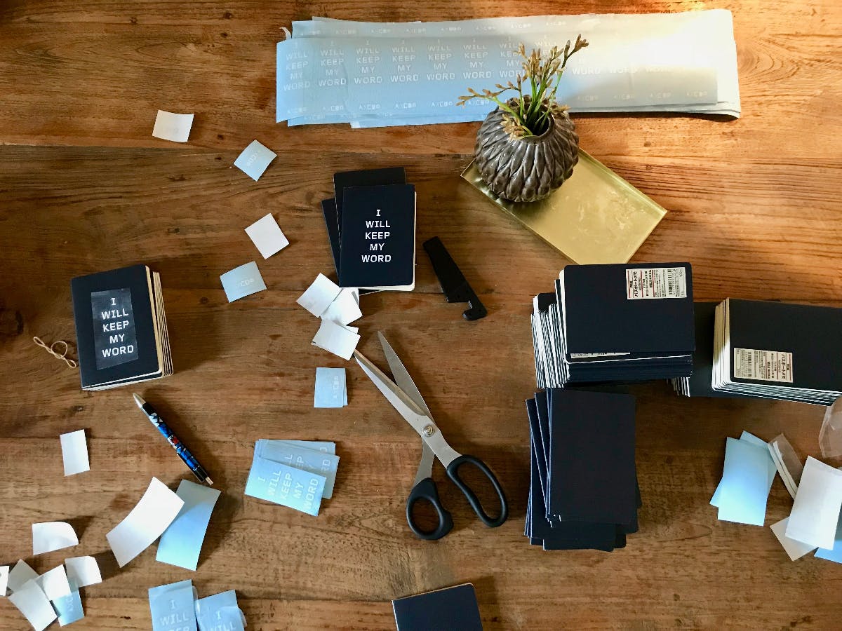 A desk covered with notebooks, stciky notes, pens, scissors and writing implaments.