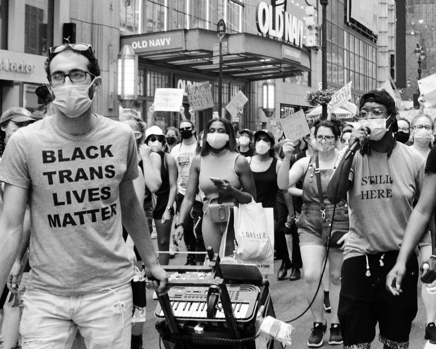 A man wearing a black trans lives matter shirt at a protest