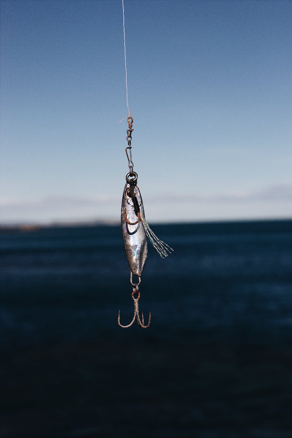 a silver three hook fishing lure dangling from a line