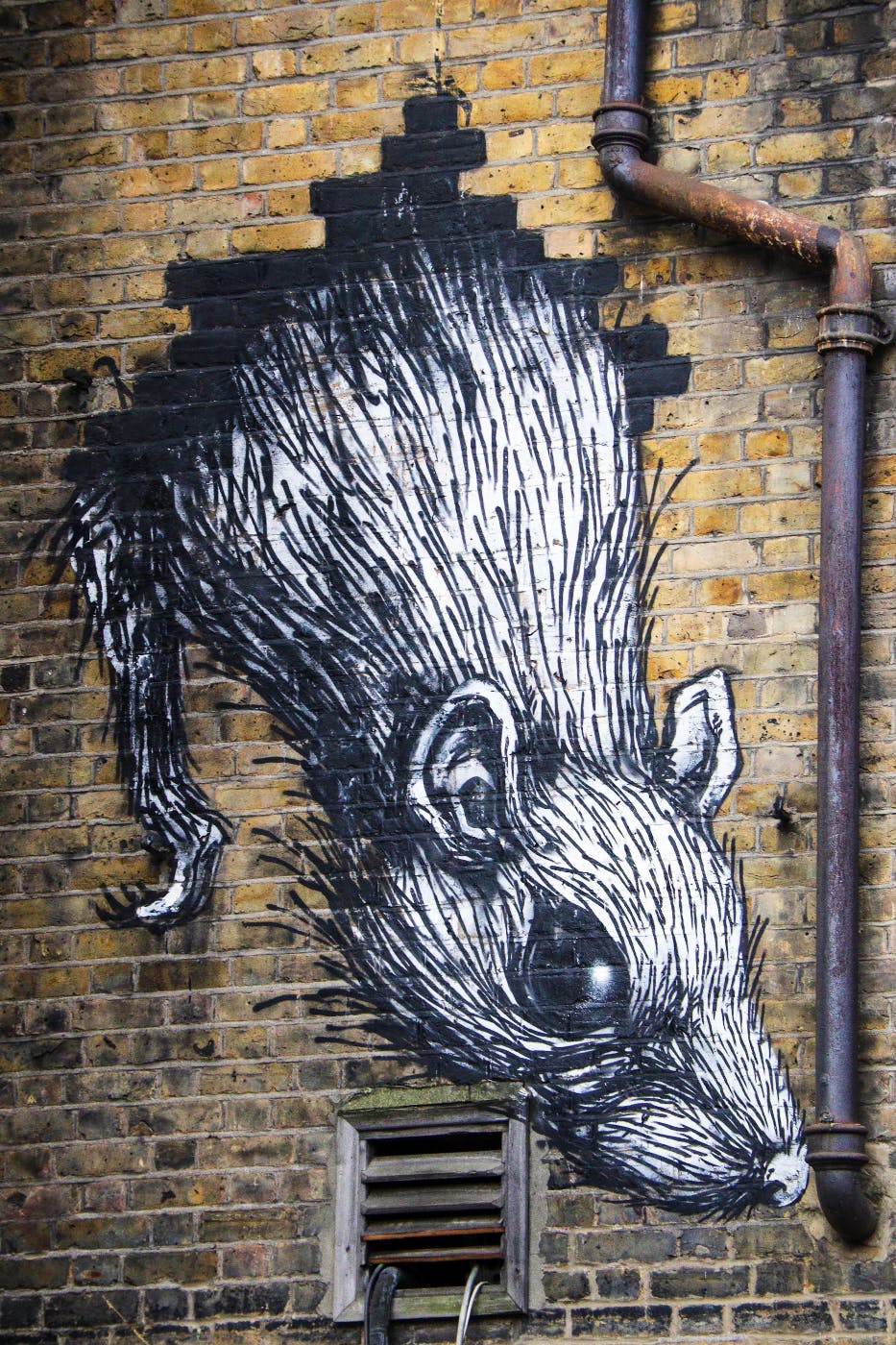 graffiti of a rat coming out of a brick wall