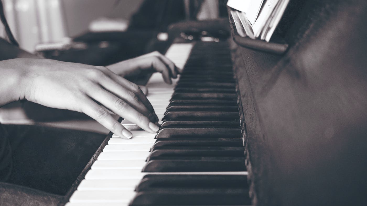 A black and white image of a woman's hands on a piano's keys