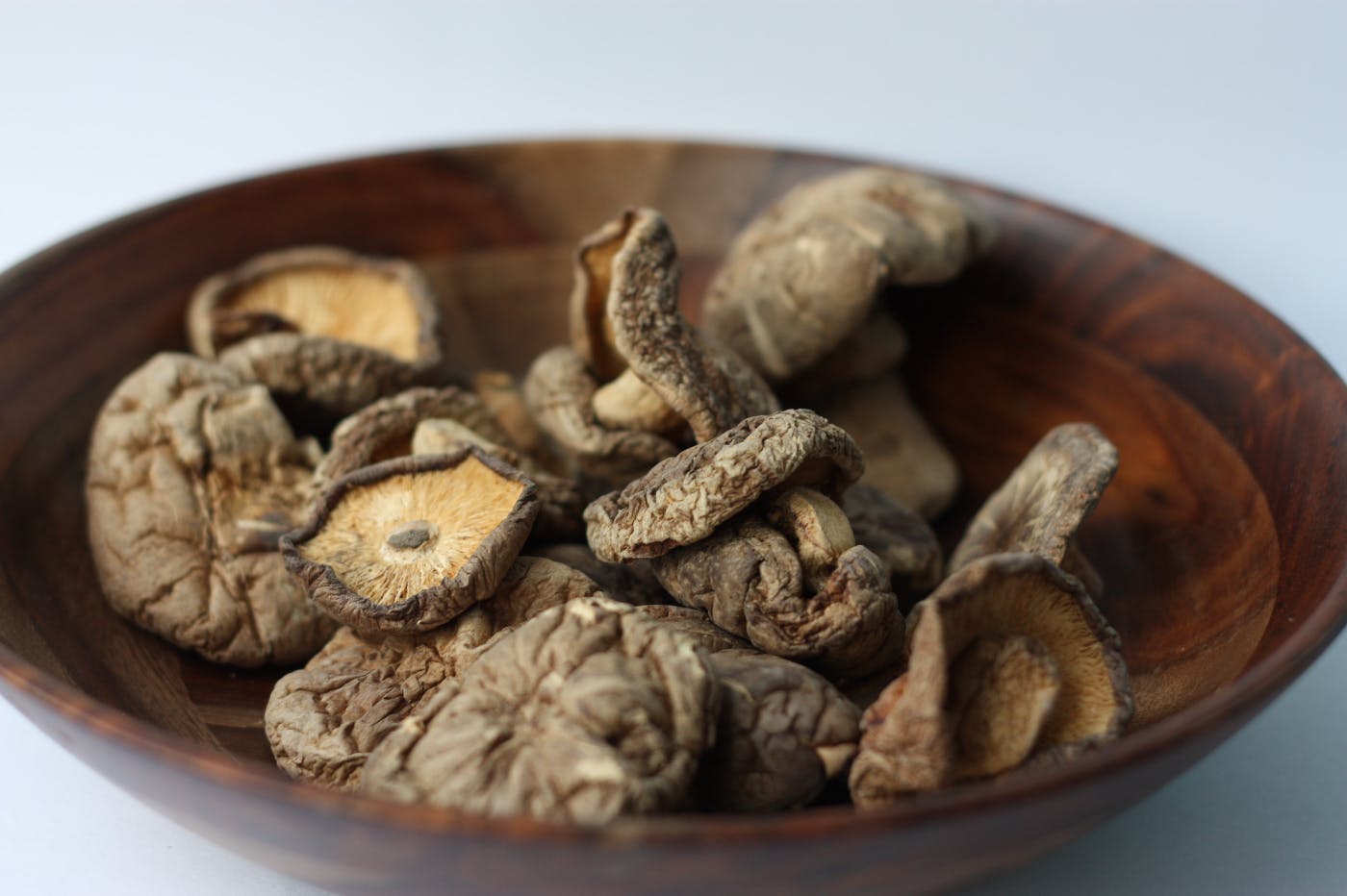 A wooden bowl of mushroom caps