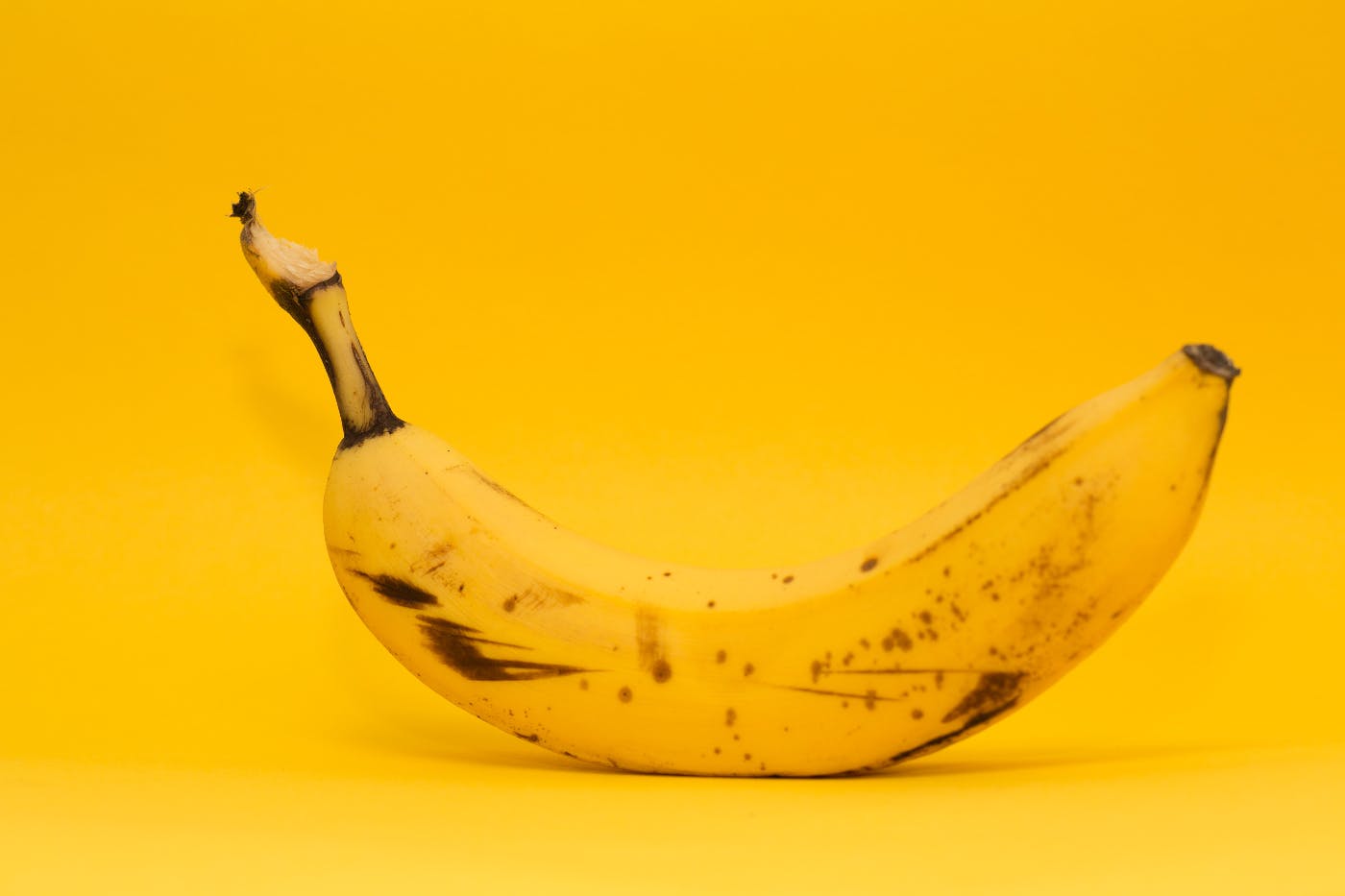 a bruised banana on a yellow background