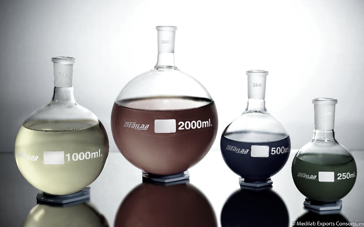 four beakers with different colored fluids in them in a lab