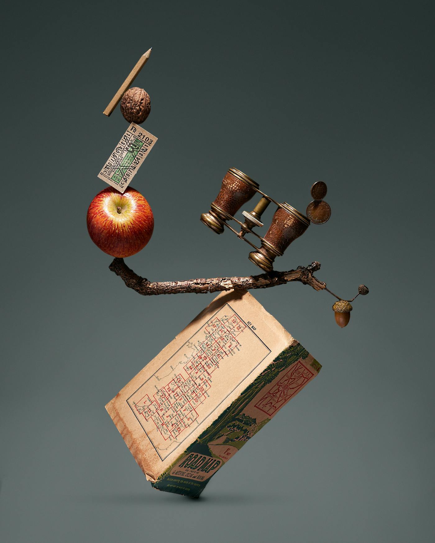 A pencil, walnut, apple, twig, opera glasses and a road map all tumbling together