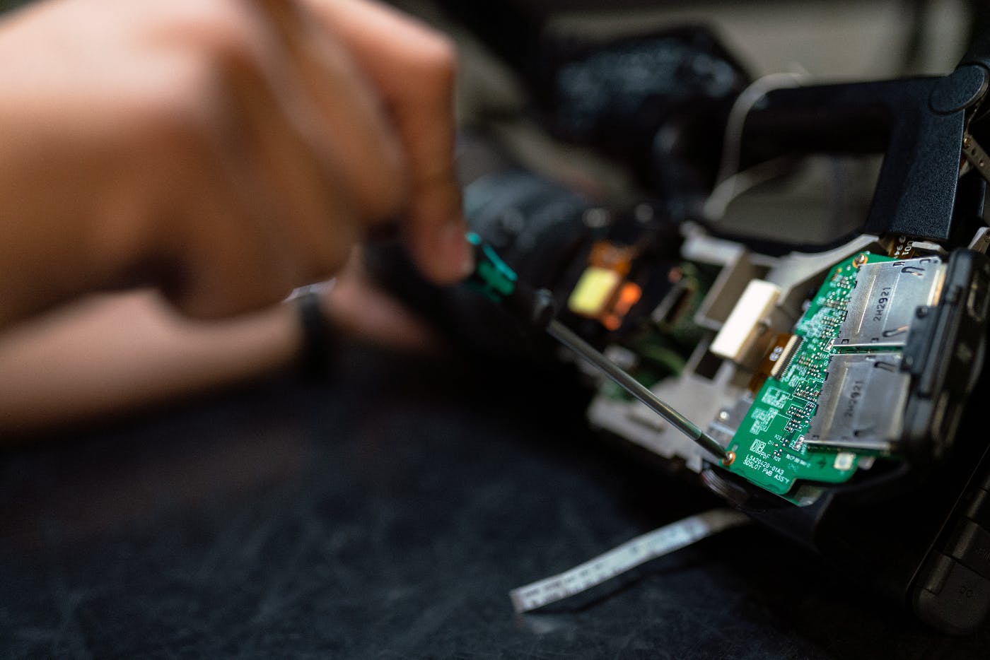 a persons hands holding a screwdriver working on a circuit board