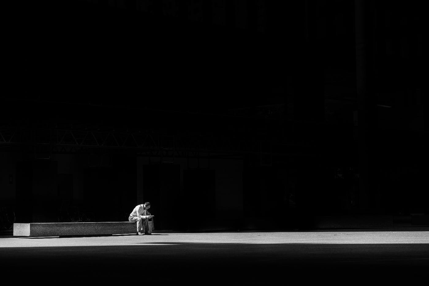 a man sitting alone on a long bench in a huge empty room