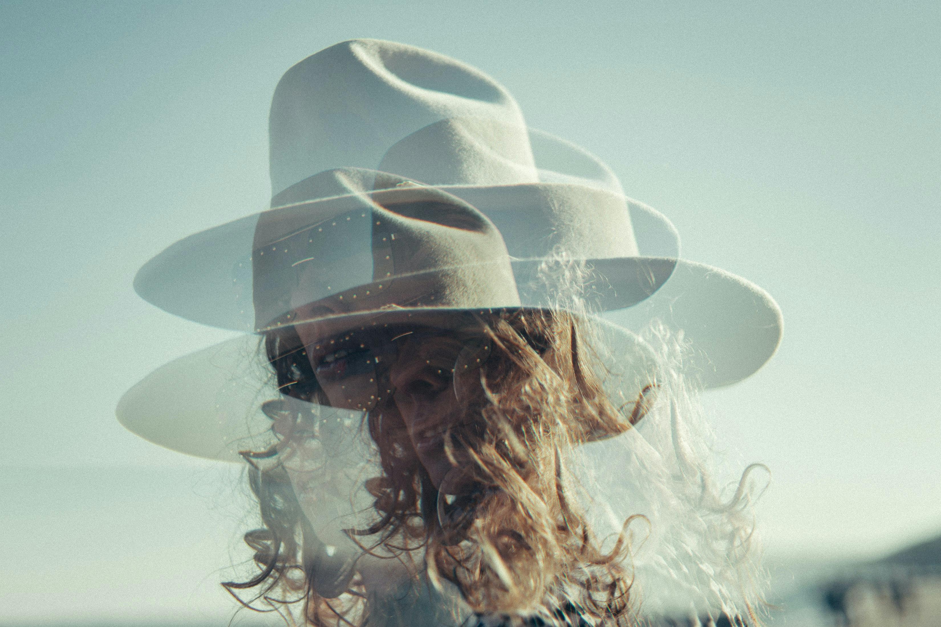 doubled image of woman in wide brim hat