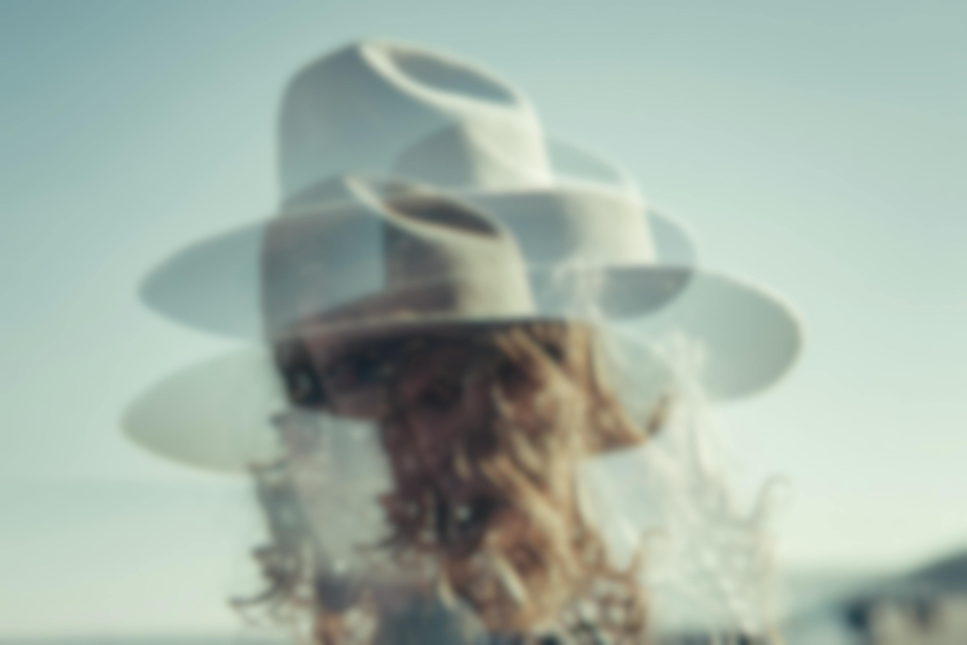 doubled image of woman in wide brim hat