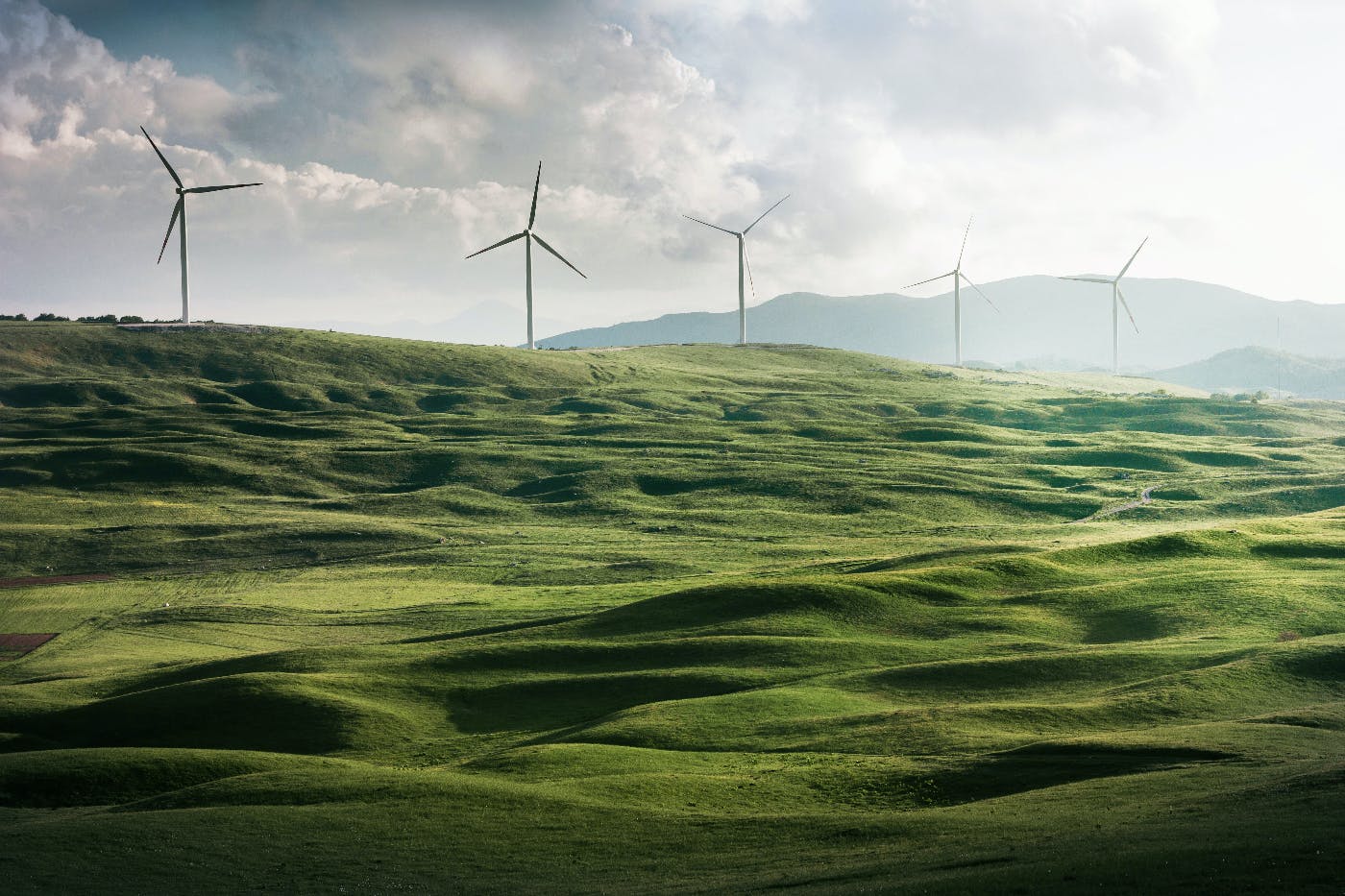 windmills overlooking a large green field with gently rolling hills