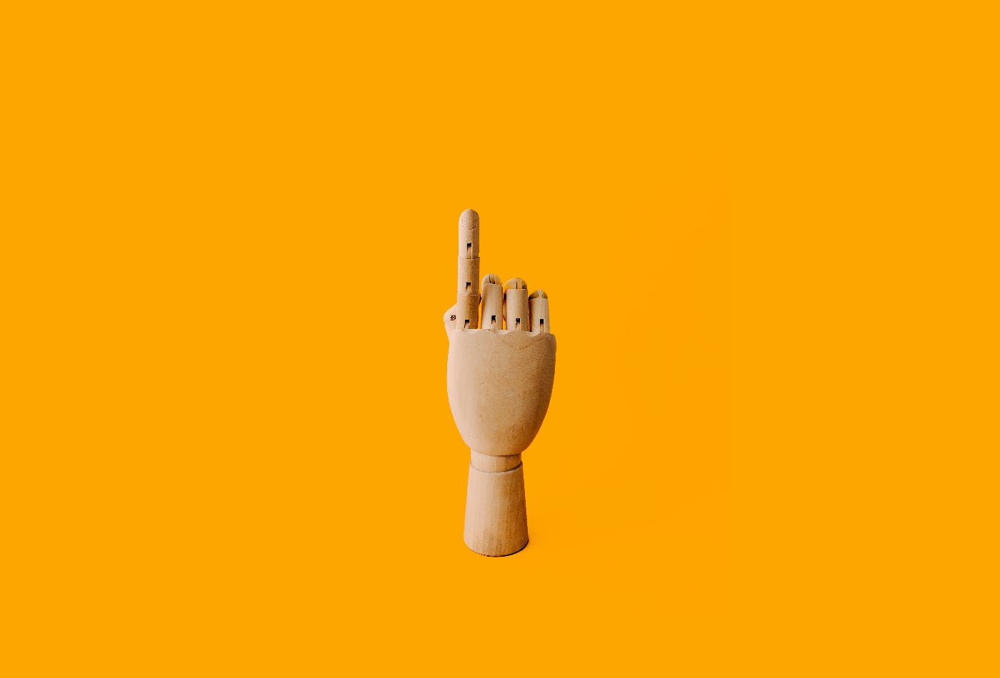 A wooden artist's model hand with the index finger up