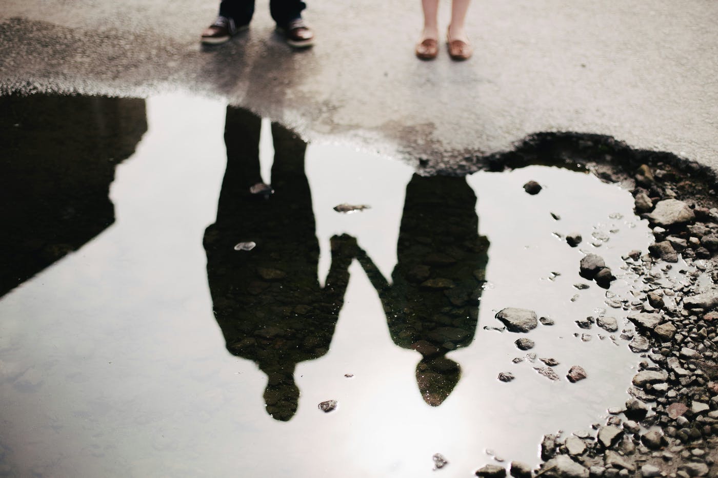 Reflection in a puddle of a couple holding hands