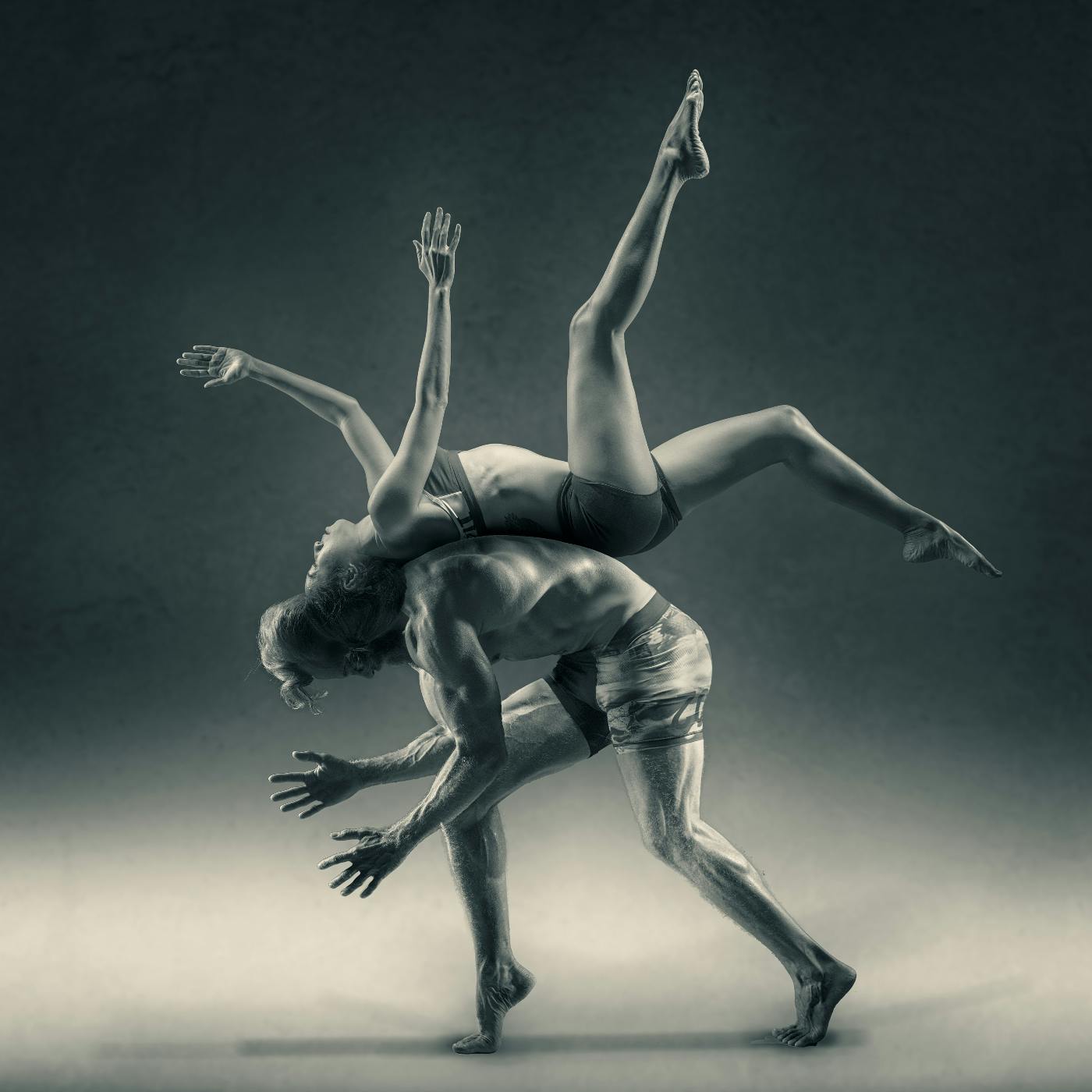 A male dancer crouched, supporting a female dancer on his back.