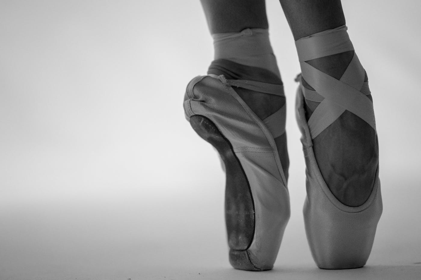 a ballerina's feet on point, in ballet slippers tied with ribbons, grayscale