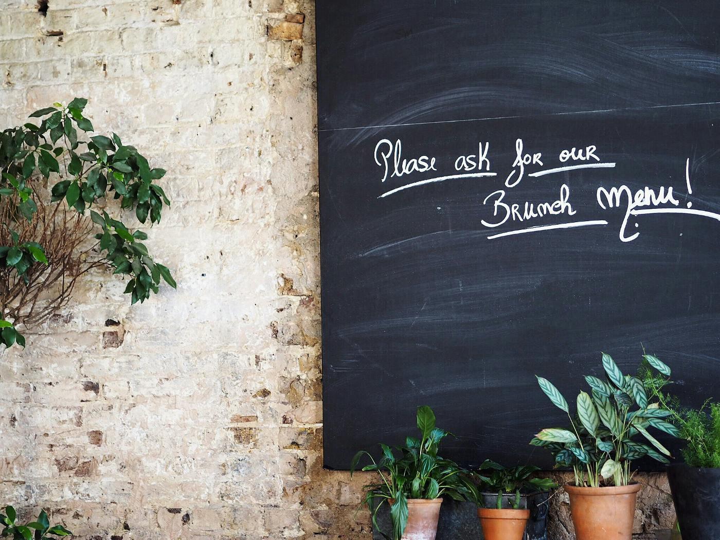 A wall with a chalk board reading Please Ask ABout Our Brunch Menu