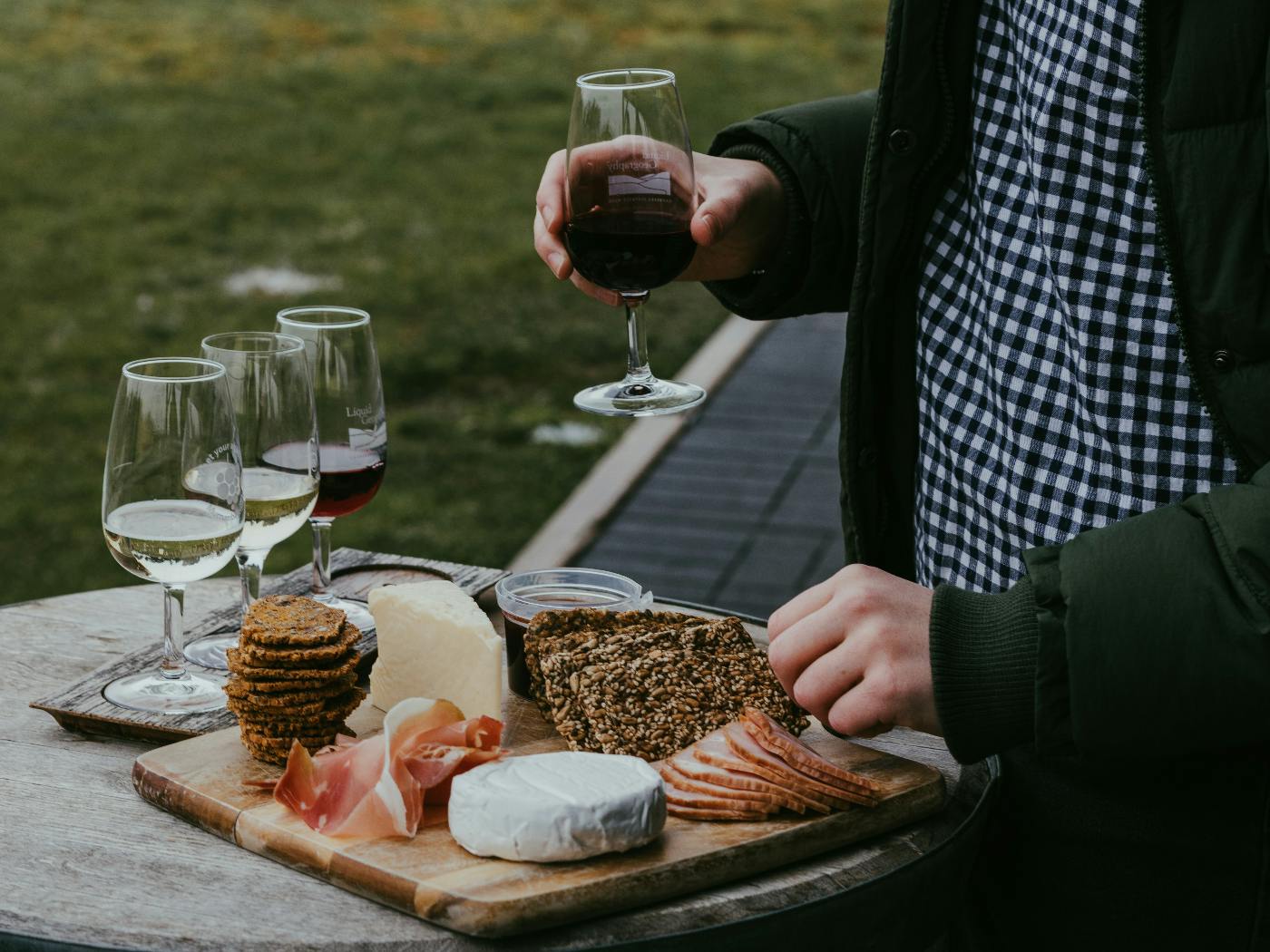 A man holding a glass of red wine, sampling from a charcuterie board