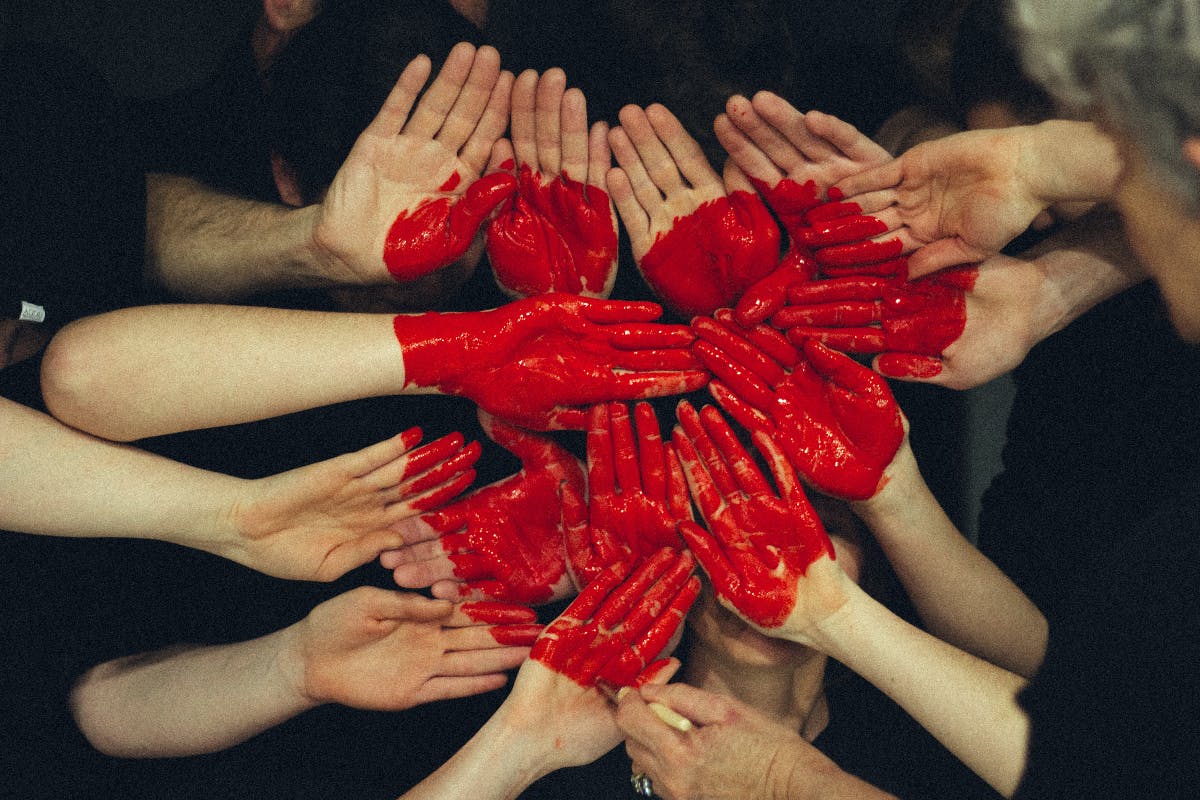 pair of hands with red paint interaction to make a heart