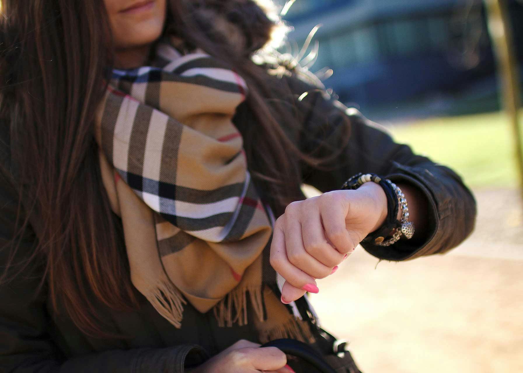 Woman wearing a Burberry scarf and checking her watch