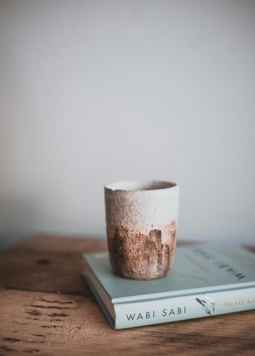 a chipped cup on top of a book titled wabi sabi