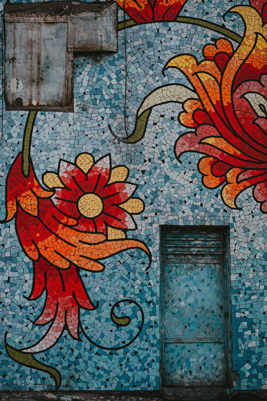 a mosaic of bright flame colored flowers on a blue wall