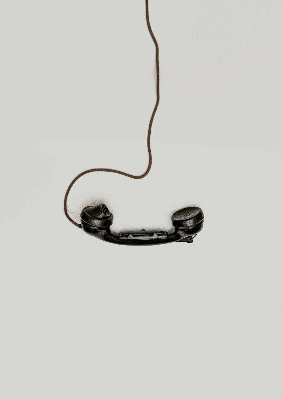 An old fashioned telephone handset in black with a chord running out of frame