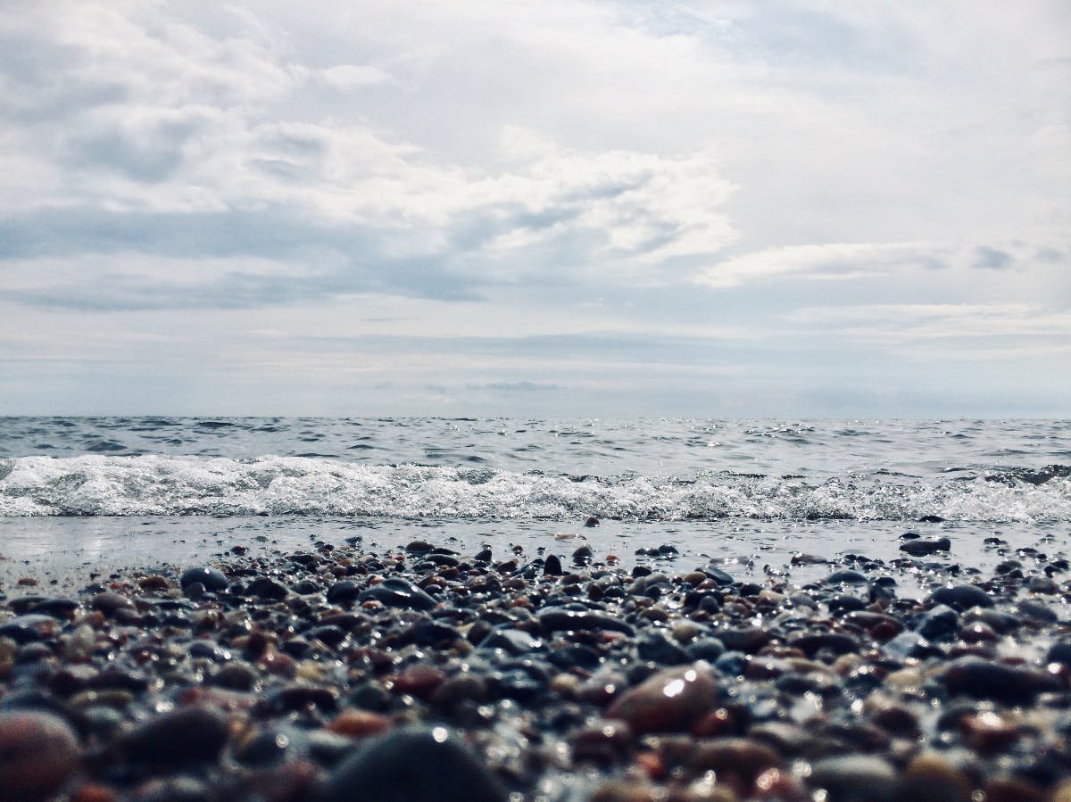 a low shot of pebbles on the beach and the ripples of the ocean