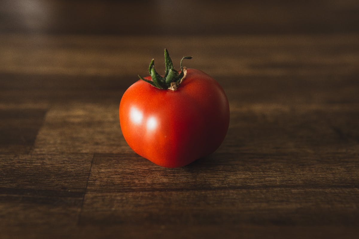 a single tomato on a cutting board