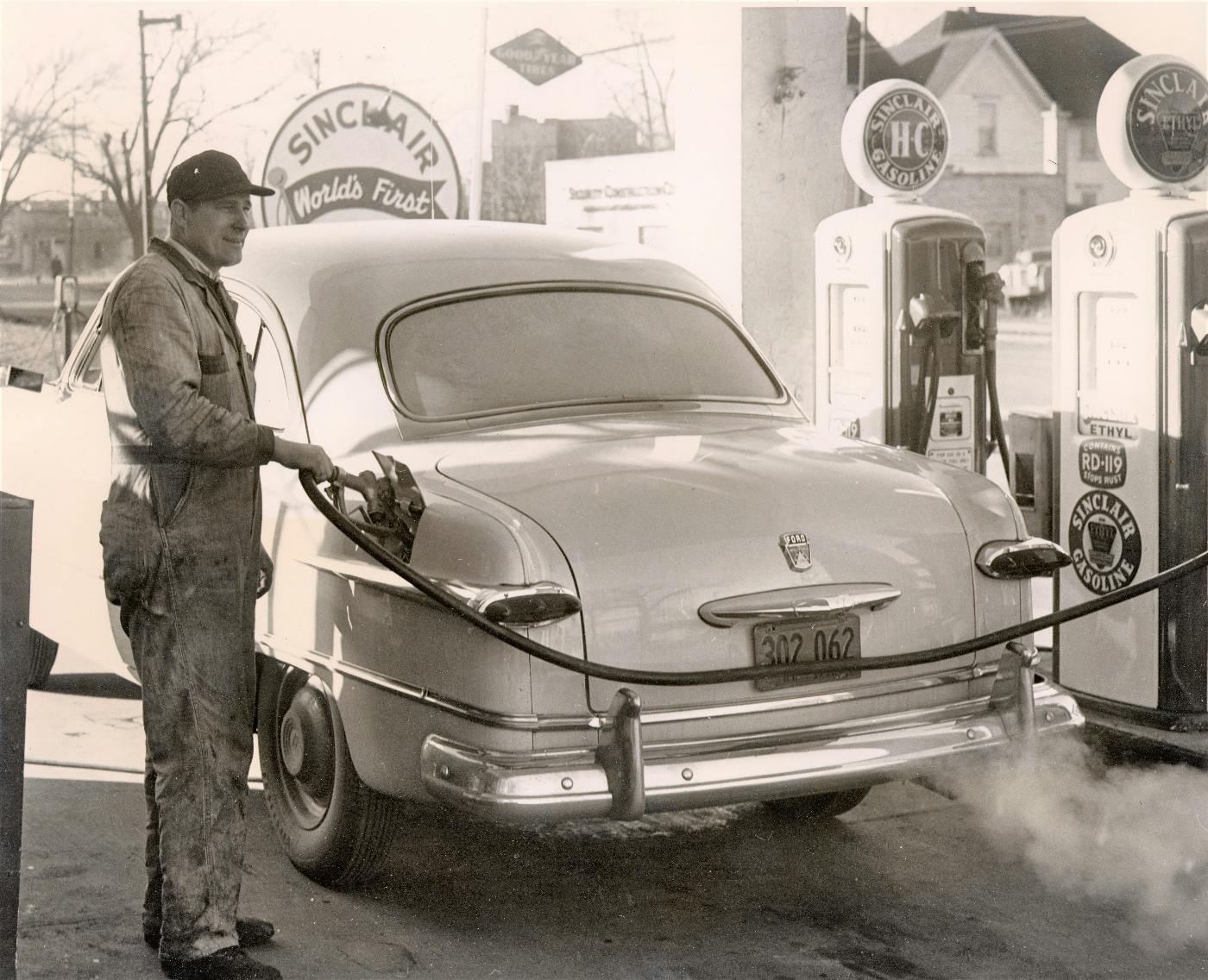 A 1850s Sinclair station with a worker filling the tank of a car