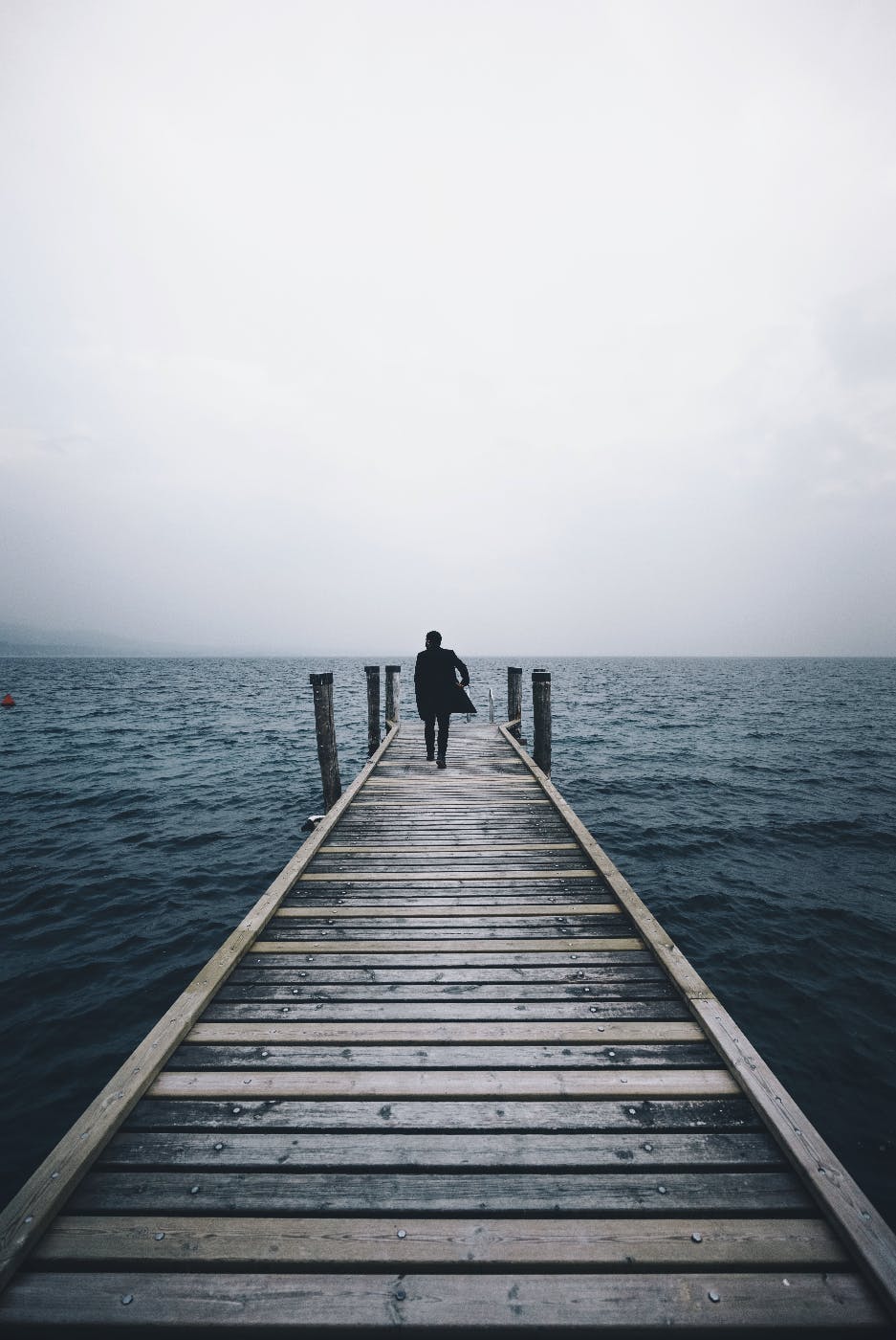 a man walking to the end of a pier to the water