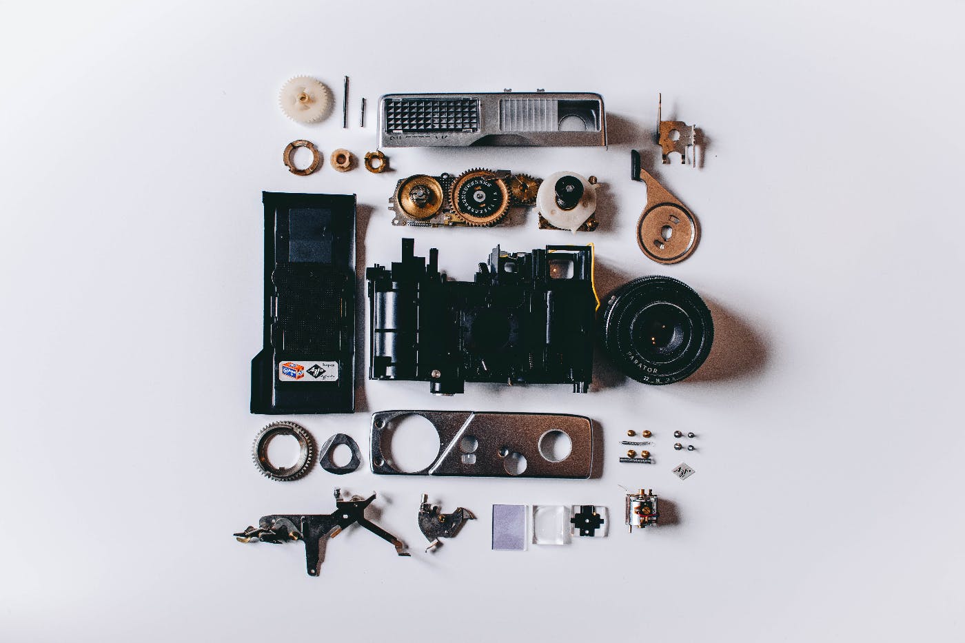 all the pieces of a film camera laid out on a pale blue background