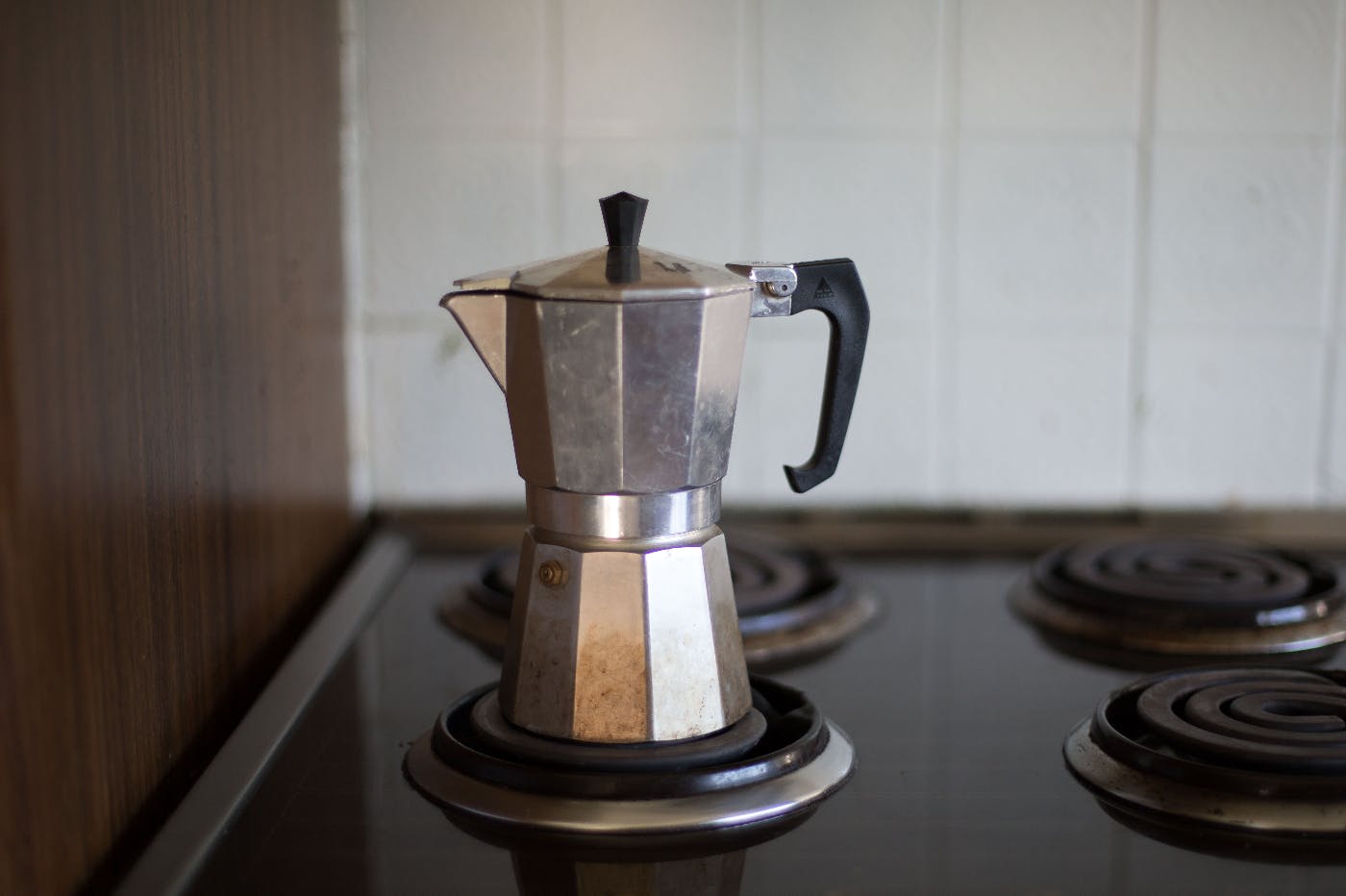 A steel coffee percolater sitting on a stove.