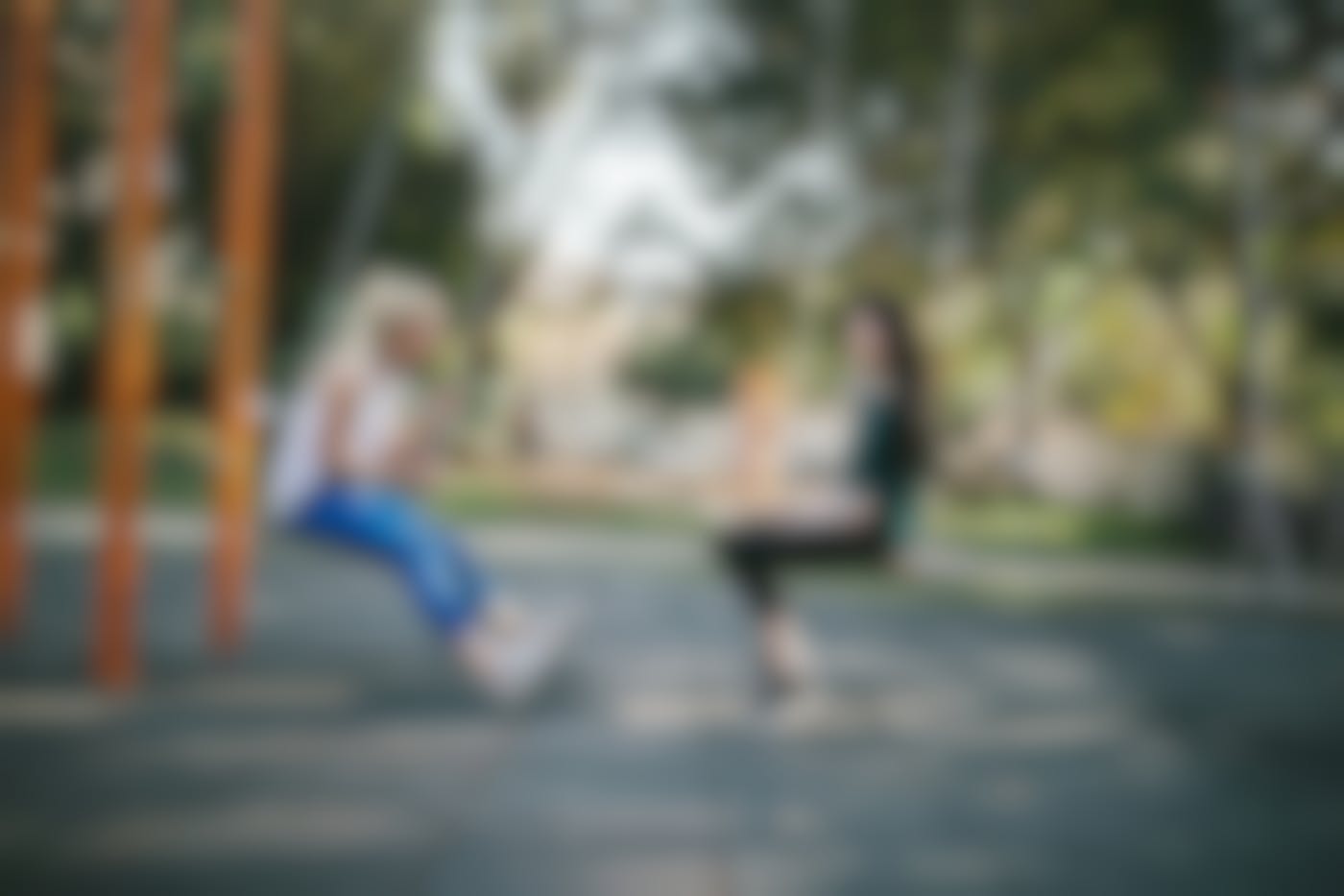 Two women on a swing set talking to each other