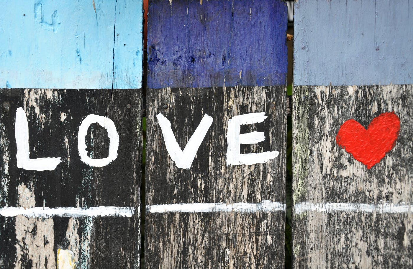 a fence with the word love and a red heart painted on it.