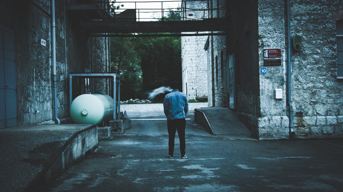 a dark toned image of a man at the edge of a city alone