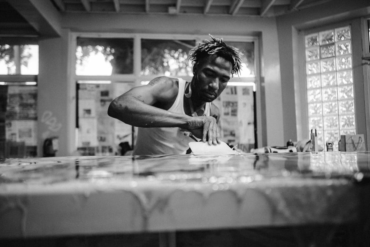 An artist working at a table moving paints with a spreader