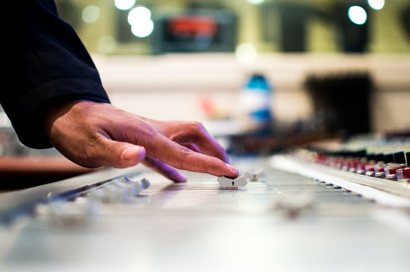 Someone making an adjustment on a sound mixing board