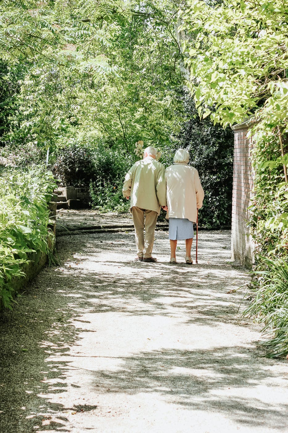 An elderly, white haired couple walkin in a park
