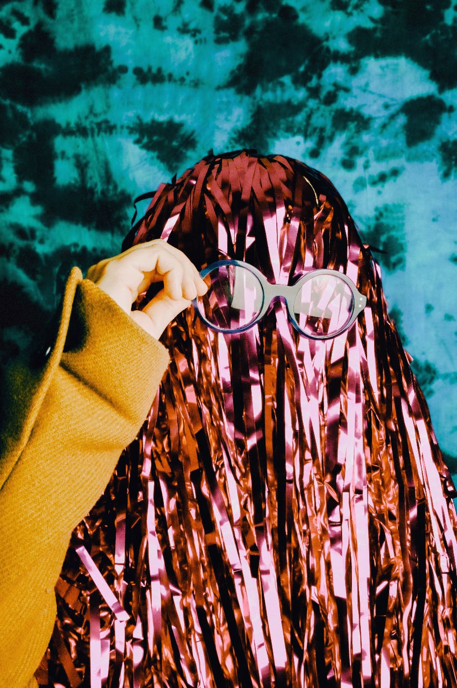 a girl with her face covered by red shimmering strands, putting on her glasses
