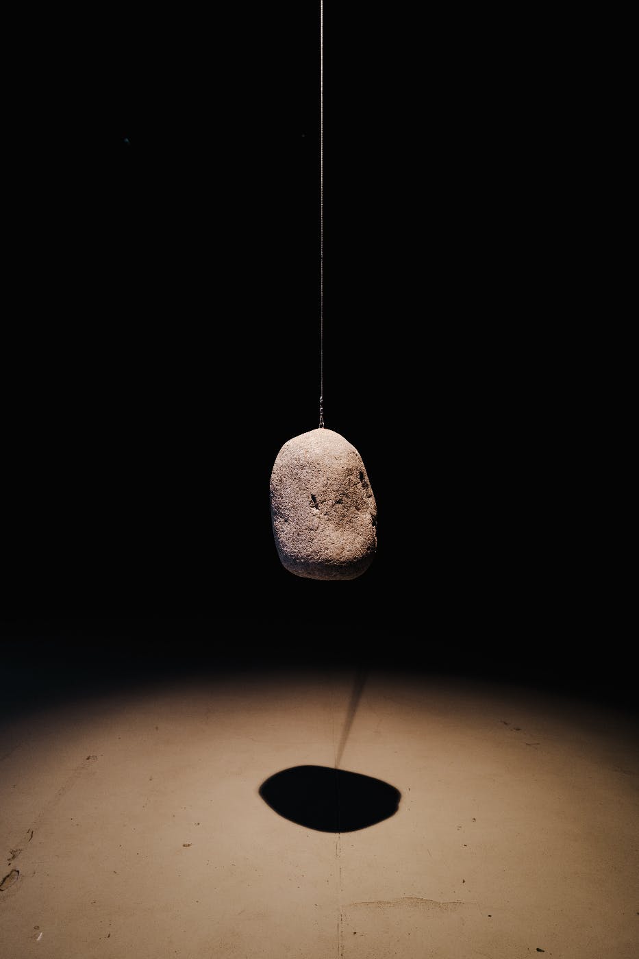 a stone suspended by a wire in a dark room