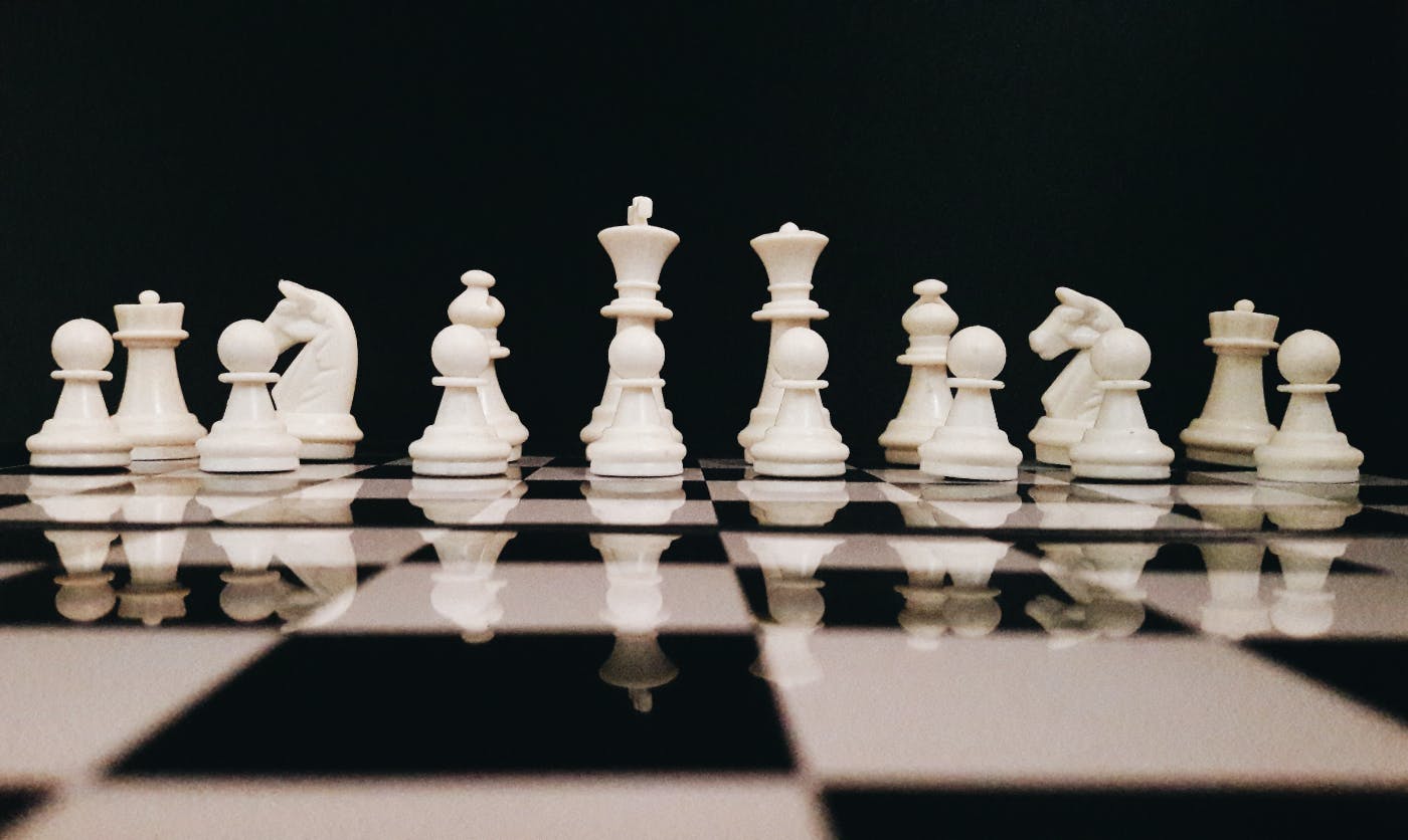 white chess pieces on a high polished chess board