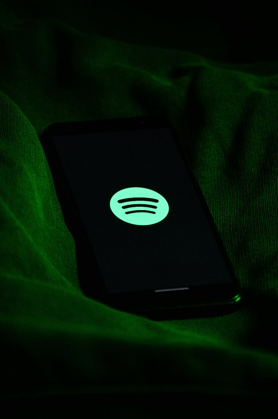 The Spotify emblem on a smartphone glowing in the dark