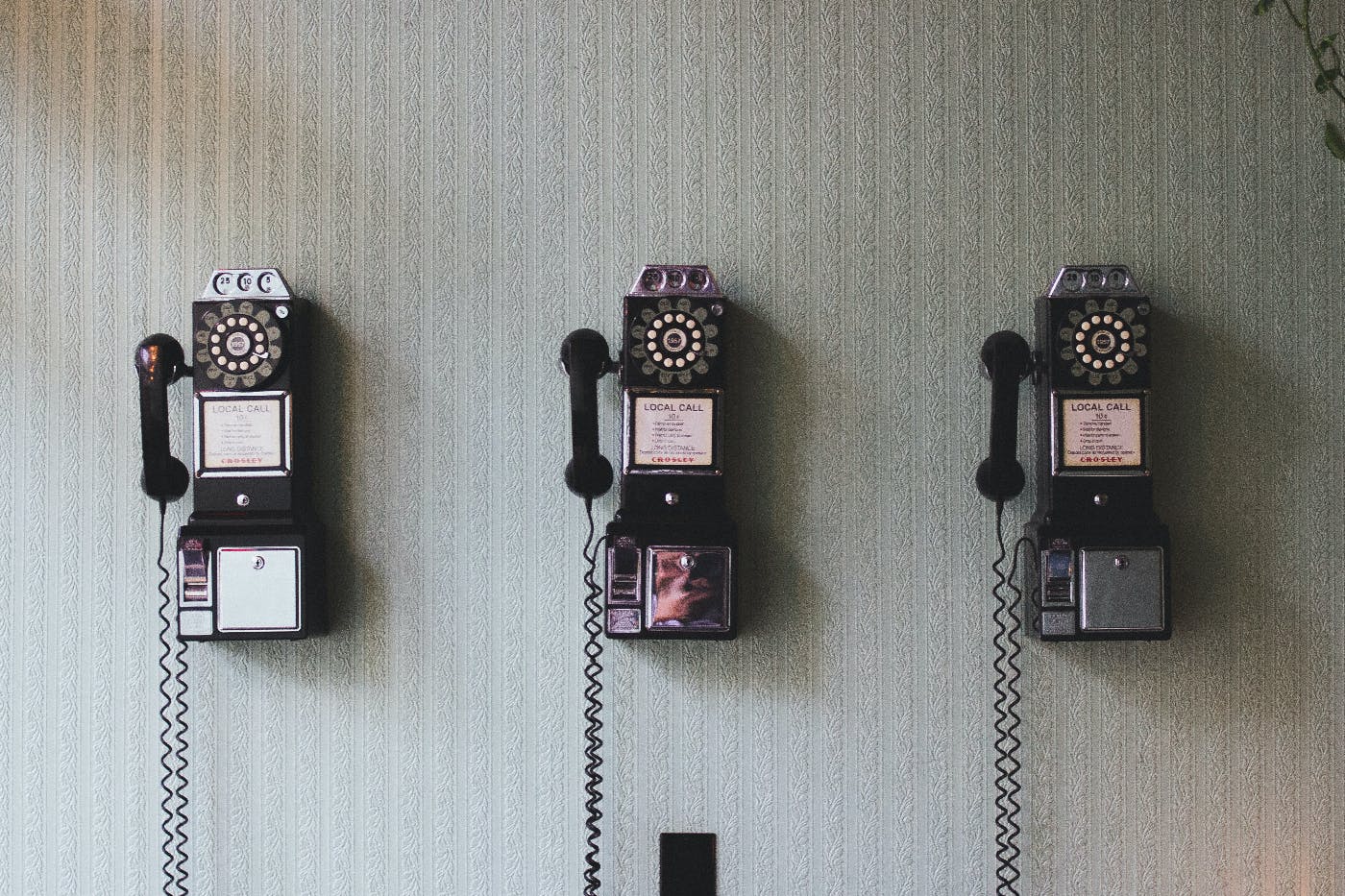 3 old fashioned payphones on a wall