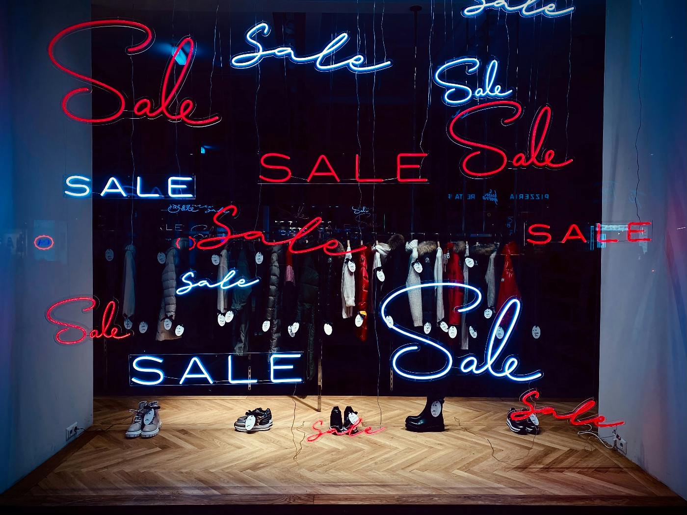 A shop window with multiple neon signs reading sale