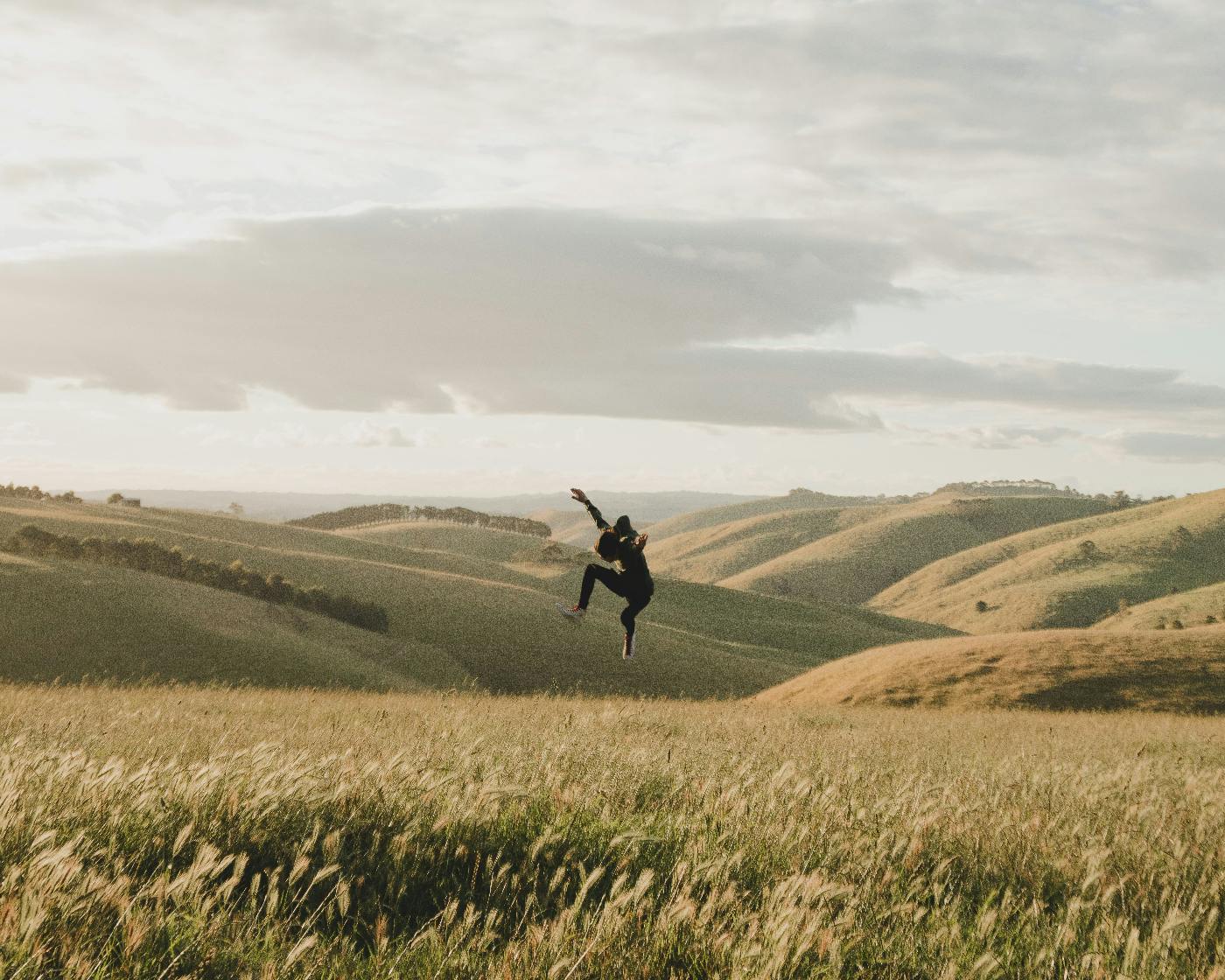 A woman dancing, floating above a field of tall grass