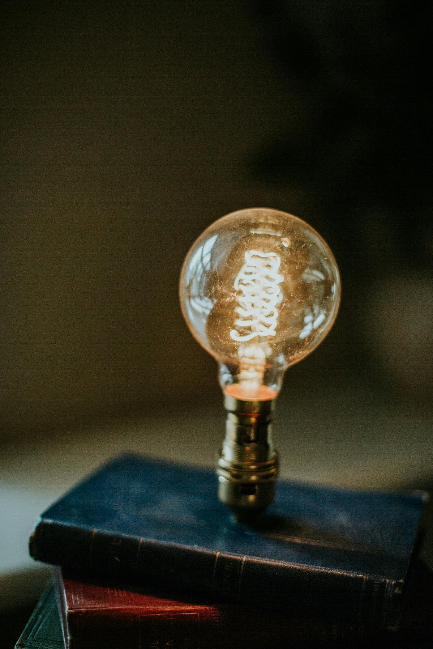 A lightbulb sitting on top of a stack of books