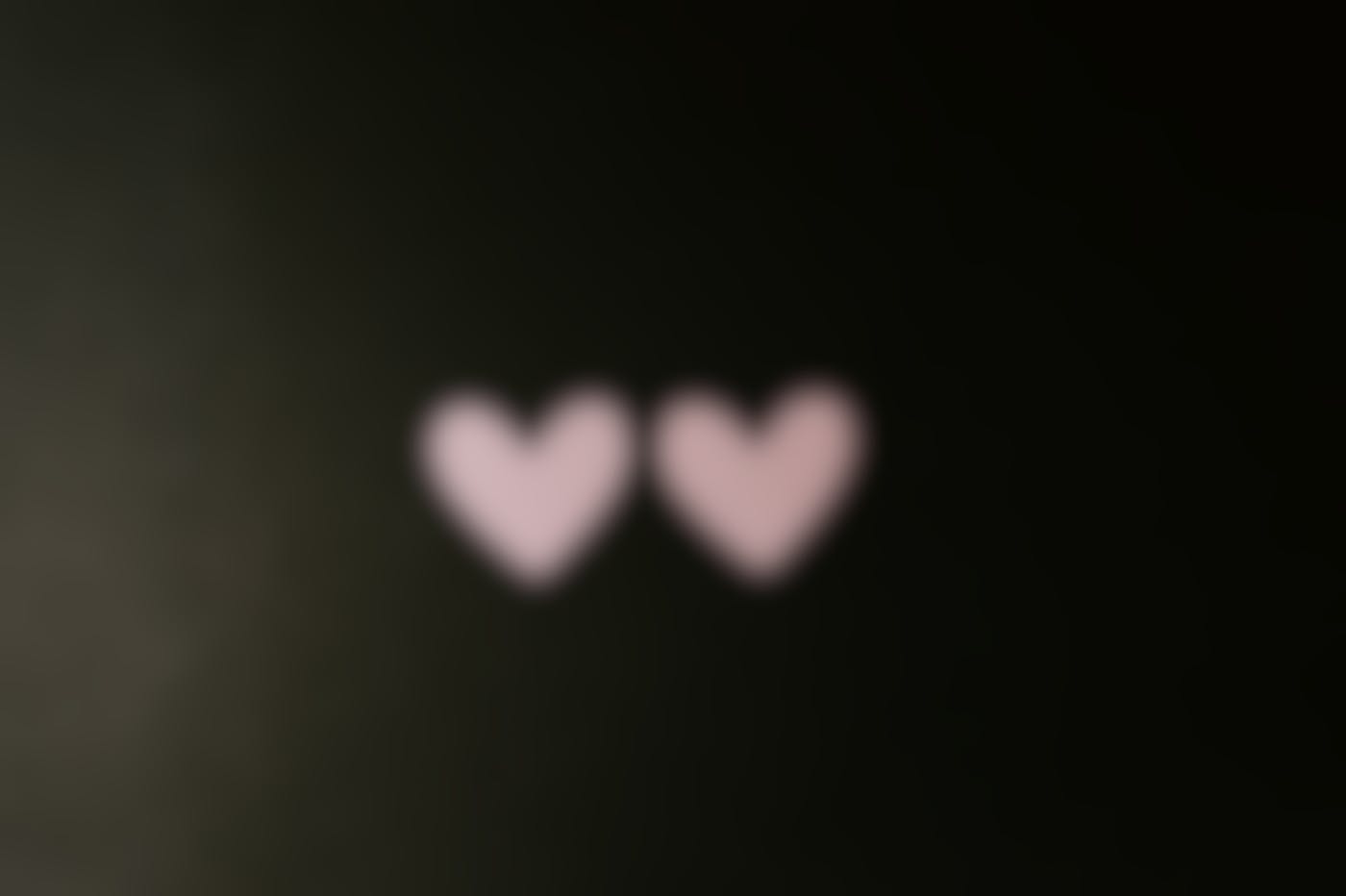 Two pink paper hearts on a black background