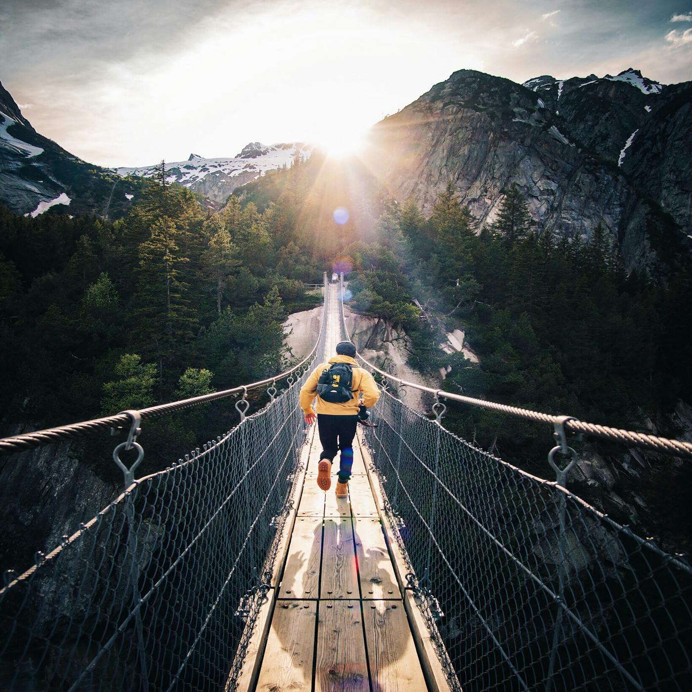 a man running across a footbridge over a chasm