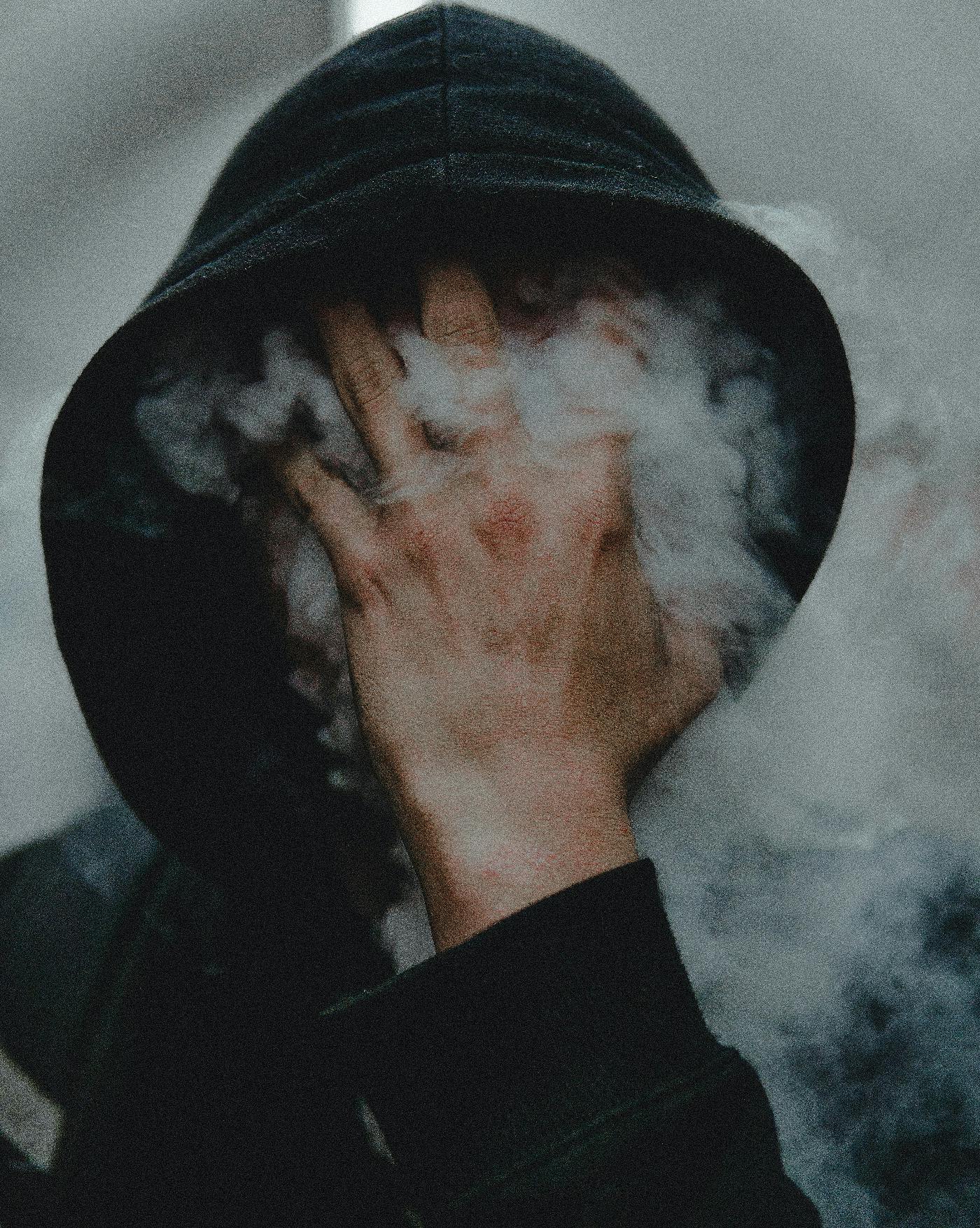 a man in a black hoody turning to smoke.